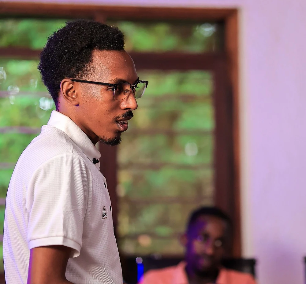 Eric Muhwezi speaking, facing toward his profile introduction
